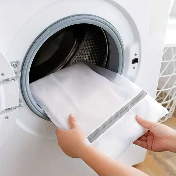 A Person is inserting cloth to a washing machine using 4 Pcs  Mesh Laundry Washing Bags Set.
