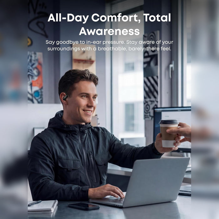 A Person is working on a laptop while wearing Anker Soundcore V40i Open-Ear True Wireless Bluetooth Earbuds and holding coffee cup in a office setup.