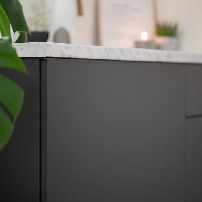 A close-up of a matte anthracite grey adhesive vinyl applied to a flat surface, likely a part of a furniture upcycling project.