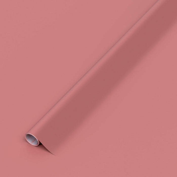 A roll of matte dusty pink vinyl film shown diagonally on a matching solid pink background.