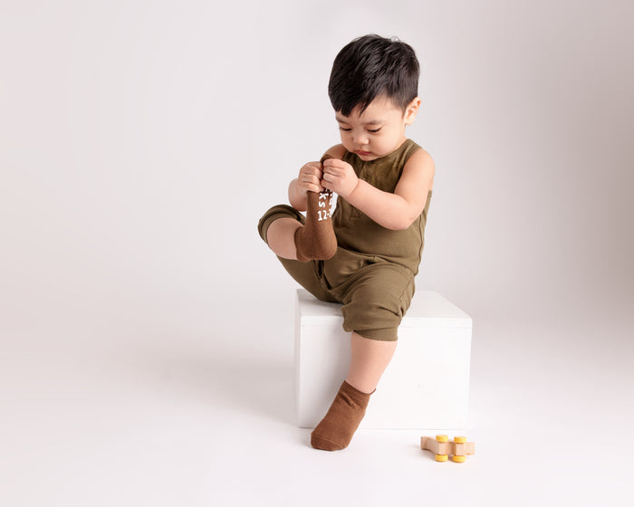 Chai ankle socks: child seated on a block wearing brown ankle socks. Squid Socks, the brand seen on Shark Tank.