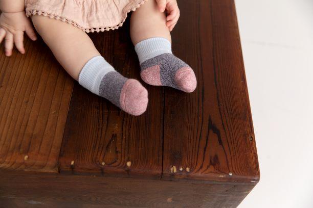 Chelsea cotton crew socks: child wearing blue-cuff crew socks on a wooden box. Squid Socks, the brand seen on Shark Tank.
