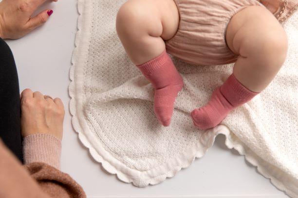 Cami kids socks: baby wearing dusty pink socks on a blanket. Squid Socks, the brand seen on Shark Tank.