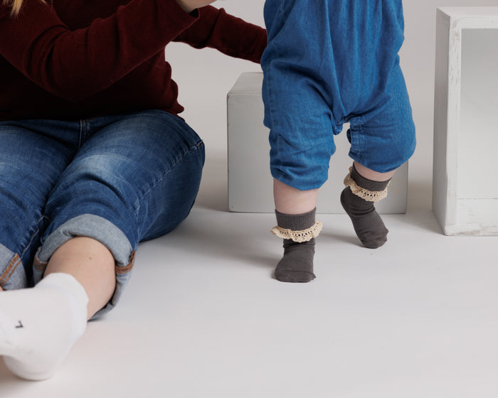 Candace kids socks: child standing in gray lace-trim socks beside a seated adult. Squid Socks, the brand seen on Shark Tank.