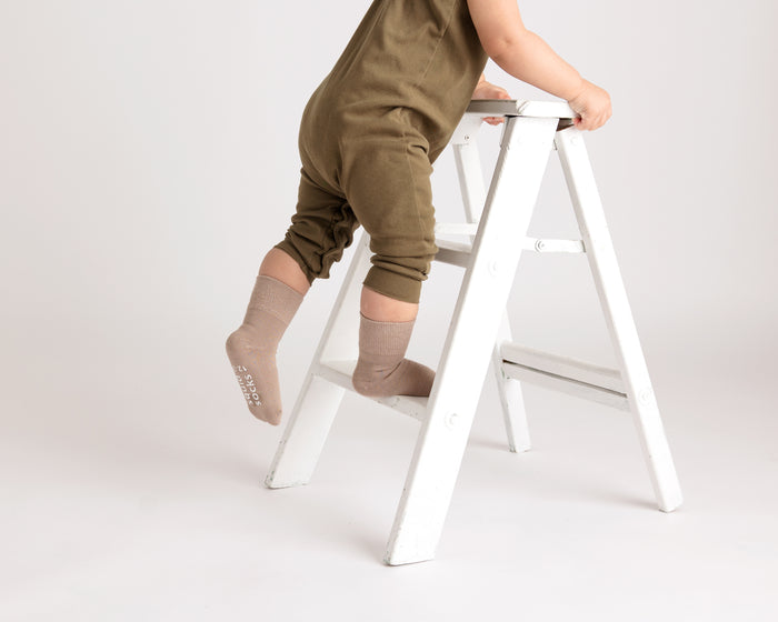 Caramel kids socks: child leaning on a chair wearing brown socks. Squid Socks, the brand seen on Shark Tank.