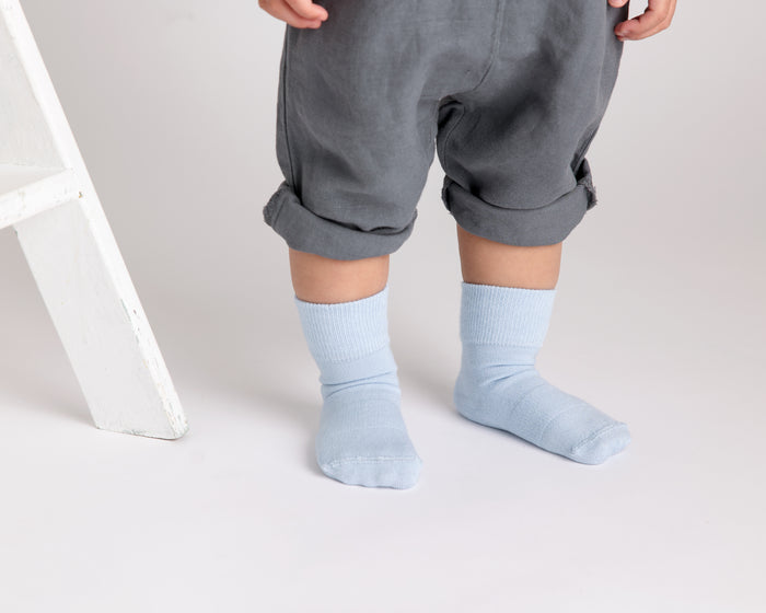 Casen kids socks: child standing in pale blue socks. Squid Socks, the brand seen on Shark Tank.