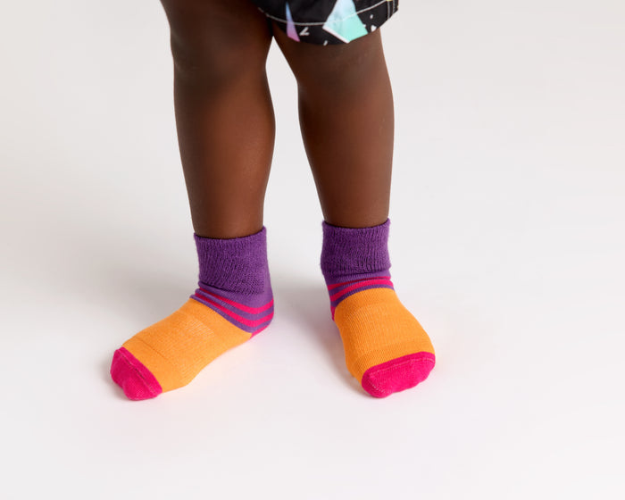 CeCe kids socks: child standing in orange socks with purple cuffs. Squid Socks, the brand seen on Shark Tank.