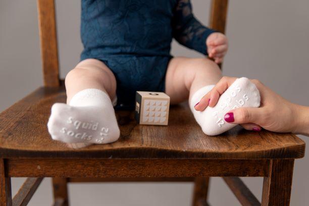 Channing kids socks: adult adjusting cream socks on a seated child. Squid Socks, the brand seen on Shark Tank.