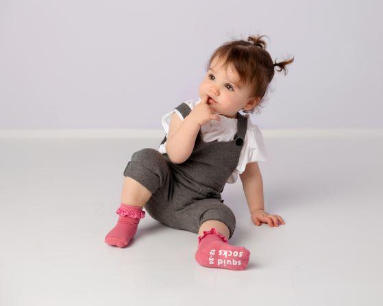 Charlotte kids socks: child seated wearing pink lace-trim socks. Squid Socks, the brand seen on Shark Tank.