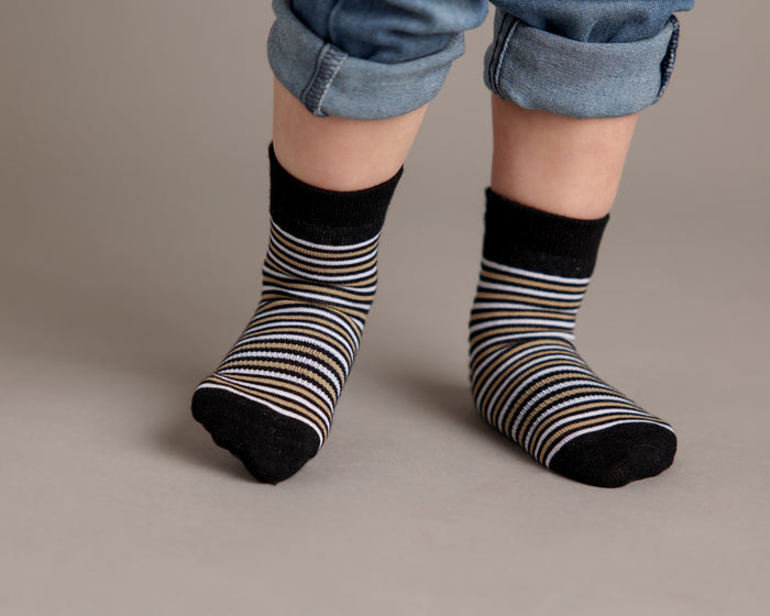 Chesney kids socks: child standing in black striped socks. Squid Socks, the brand seen on Shark Tank.