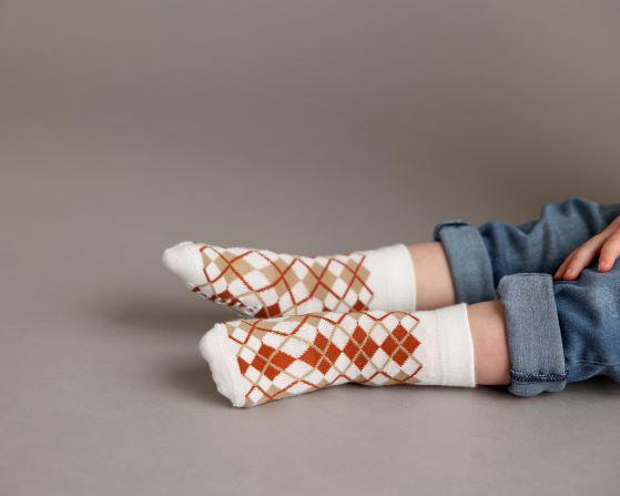 Chesney kids socks: child seated wearing white and brown argyle socks. Squid Socks, the brand seen on Shark Tank.