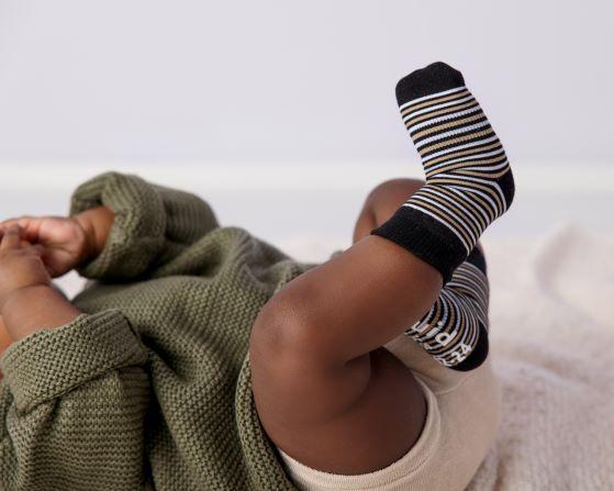 Chesney kids socks: baby lying down wearing black striped socks. Squid Socks, the brand seen on Shark Tank.