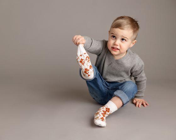Chesney kids socks: child seated holding a foot in an argyle sock. Squid Socks, the brand seen on Shark Tank.