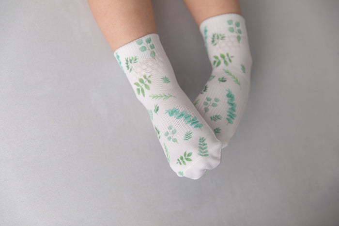 Chloe kids socks: child wearing white socks with green foliage print. Squid Socks, the brand seen on Shark Tank.