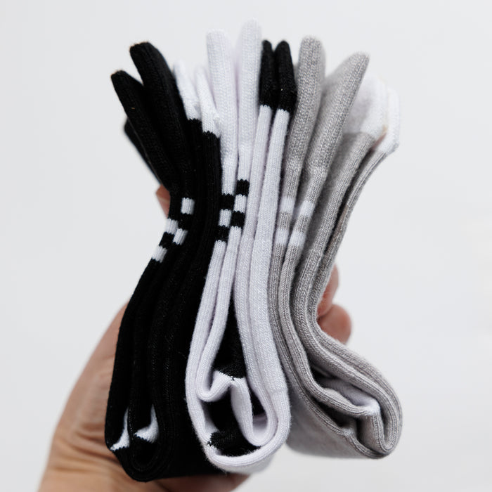 City kids socks: hand holding a stack of white, gray and black socks. Squid Socks, the brand seen on Shark Tank.