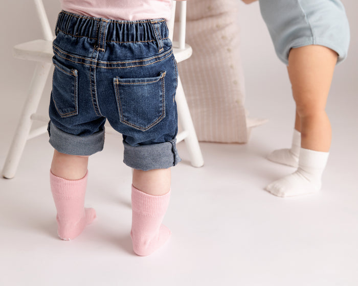 Claire kids socks: child standing in soft pink socks beside another child. Squid Socks, the brand seen on Shark Tank.