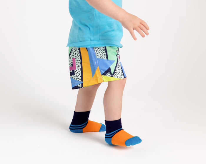 Clint kids socks: child standing in orange socks with navy cuffs. Squid Socks, the brand seen on Shark Tank.