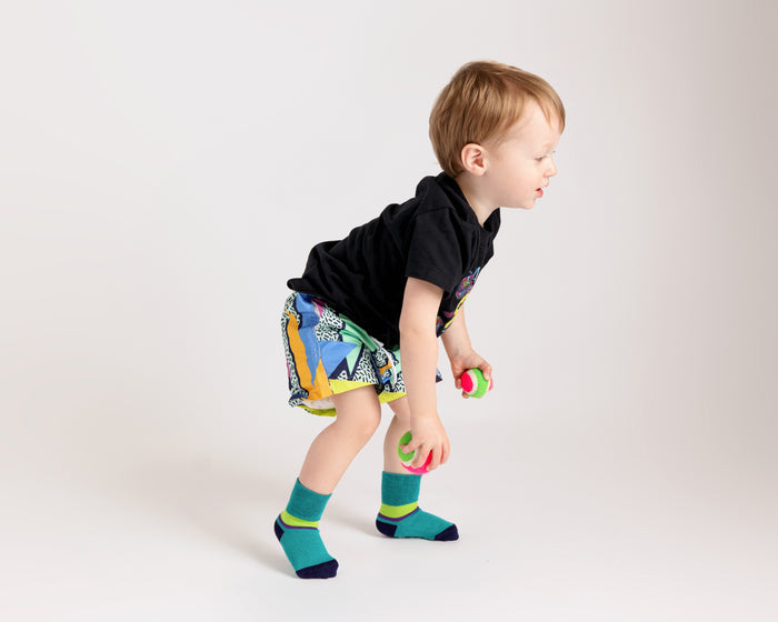 Clint kids socks: child bending down in teal socks. Squid Socks, the brand seen on Shark Tank.