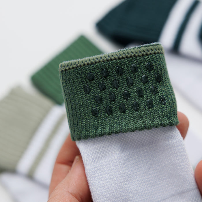 Cooper kids socks: hand holding a green cuff to show silicone grip dots. Squid Socks, the brand seen on Shark Tank.