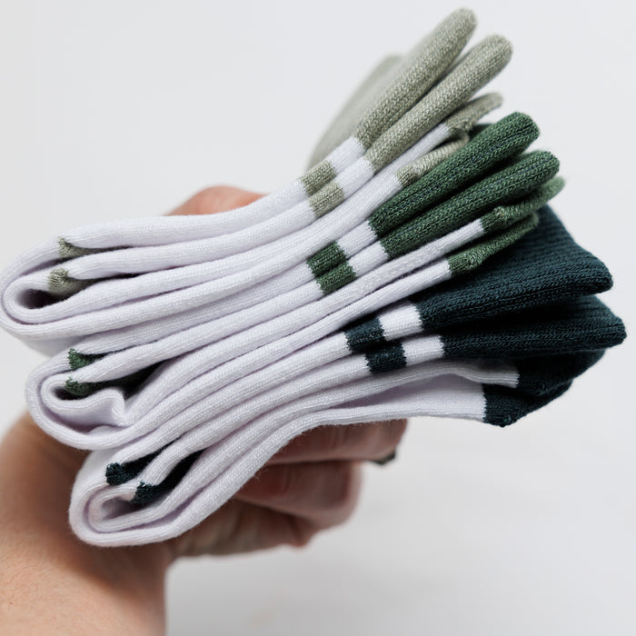 Cooper kids socks: hand holding a stack of white and green socks. Squid Socks, the brand seen on Shark Tank.