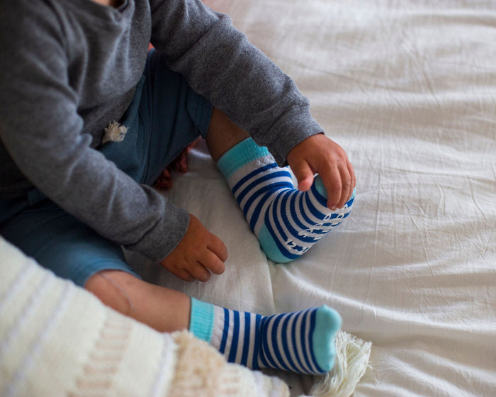 Cruz kids socks: child seated wearing blue striped socks. Squid Socks, the brand seen on Shark Tank.