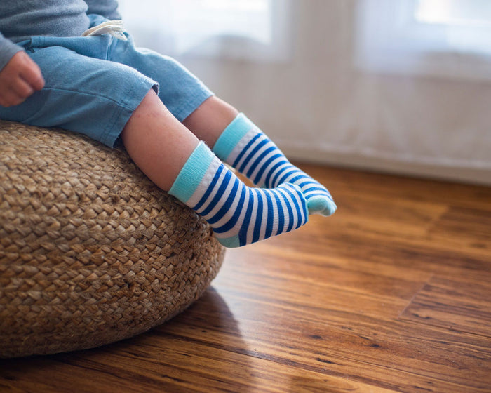 Cruz kids socks: child seated with blue striped socks dangling. Squid Socks, the brand seen on Shark Tank.