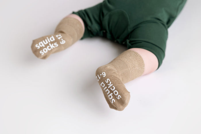 Cypress kids socks: baby lying down showing saddle brown sock soles. Squid Socks, the brand seen on Shark Tank.