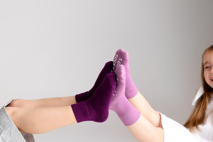 Orchid kids socks: children touching socked feet in lavender and plum. Squid Socks, the brand seen on Shark Tank.