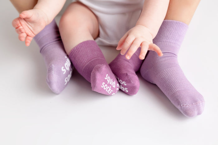 Orchid kids socks: children seated together wearing purple-toned socks. Squid Socks, the brand seen on Shark Tank.