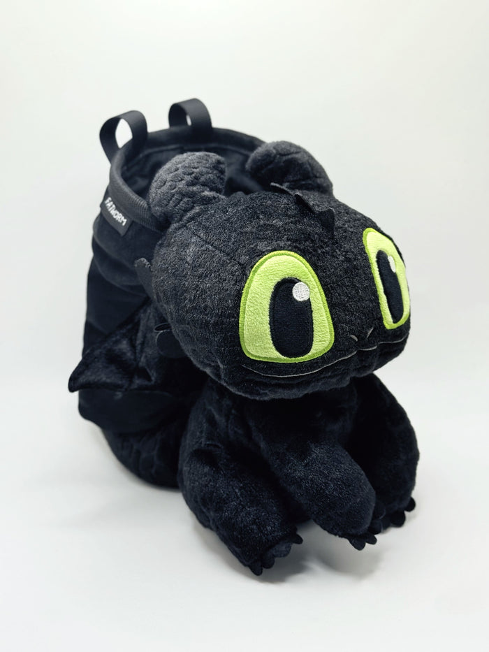 A soft and fluffy Baby Toothless Night Fury plush chalk bag by Fatworm. This cute and functional bouldering accessory features tiny wings, emerald eyes, and a long-durable handmade design. A perfect climbing gift for climbers who love unique dragon-inspired gear.