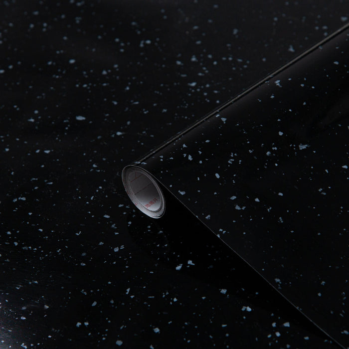 Roll of black vinyl wrap with a speckled pattern on a dark background