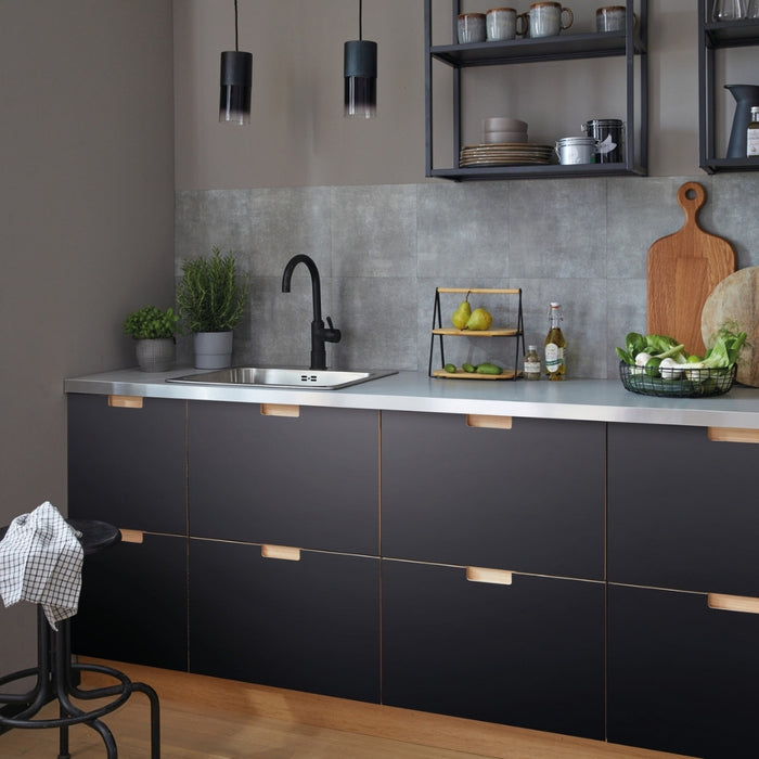 A kitchen setting featuring black matte adhesive vinyl used on cabinet surfaces and drawers, with a modern interior decor.