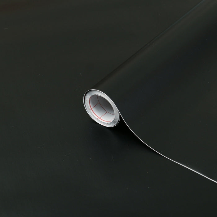 A black matte adhesive vinyl roll on a black matte background.