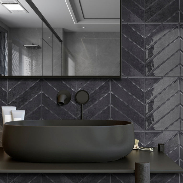 Modern bathroom with a black sink against a chevron-patterned wall.