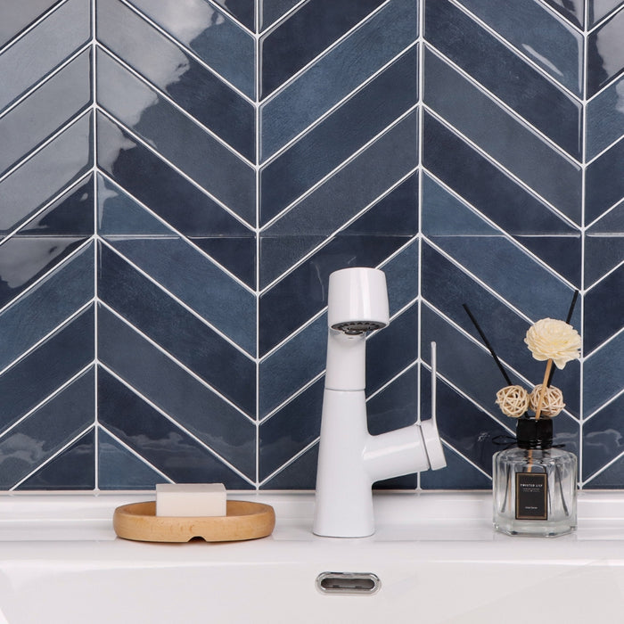 White faucet on a sink with blue chevron tiled wall