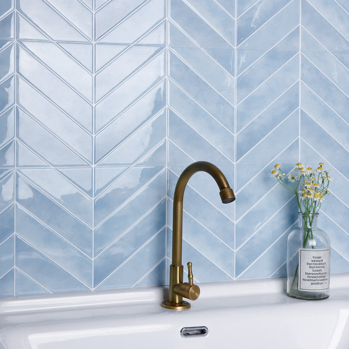 Kitchen sink with a gold faucet against a blue tiled wall
