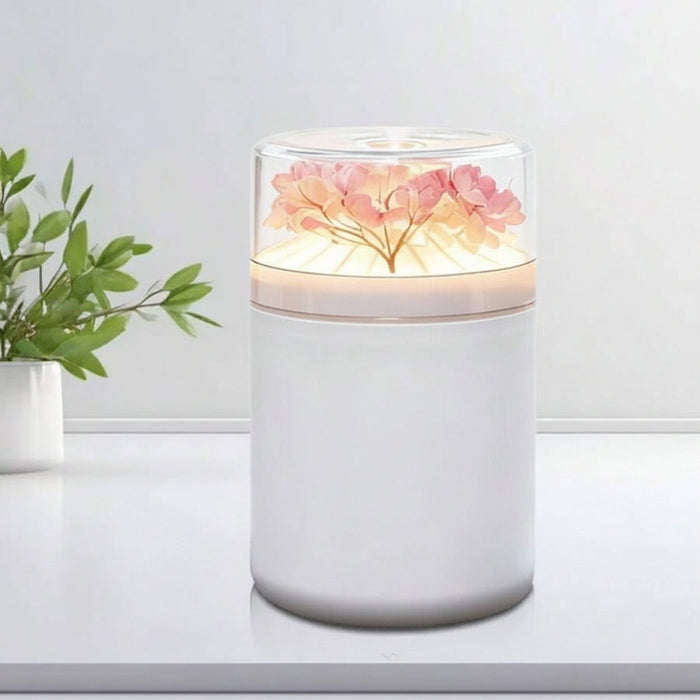 Humidifier with floral design on top, dimensions indicated, and plant in the background.