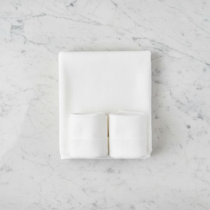 White folded Cotton Bath & Face Towel Set on a marble surface