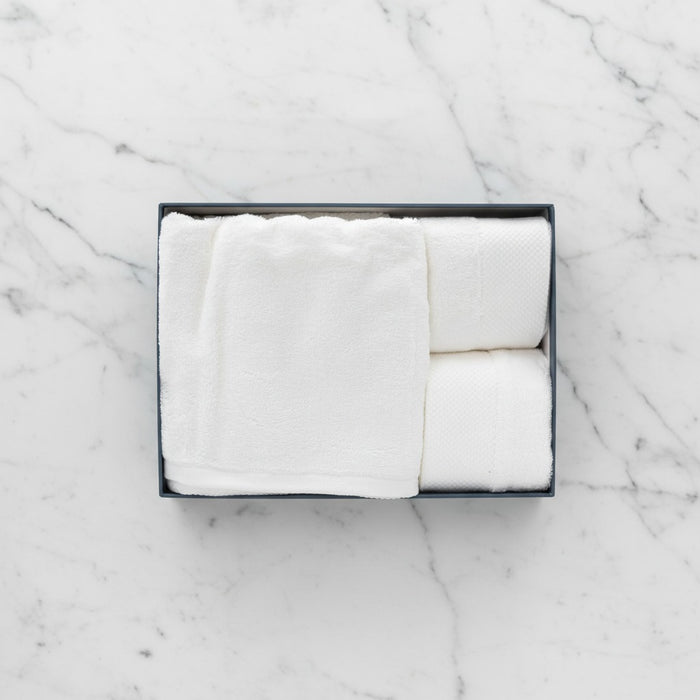 White folded Cotton Bath & Face Towel Set in a black box on a marble surface