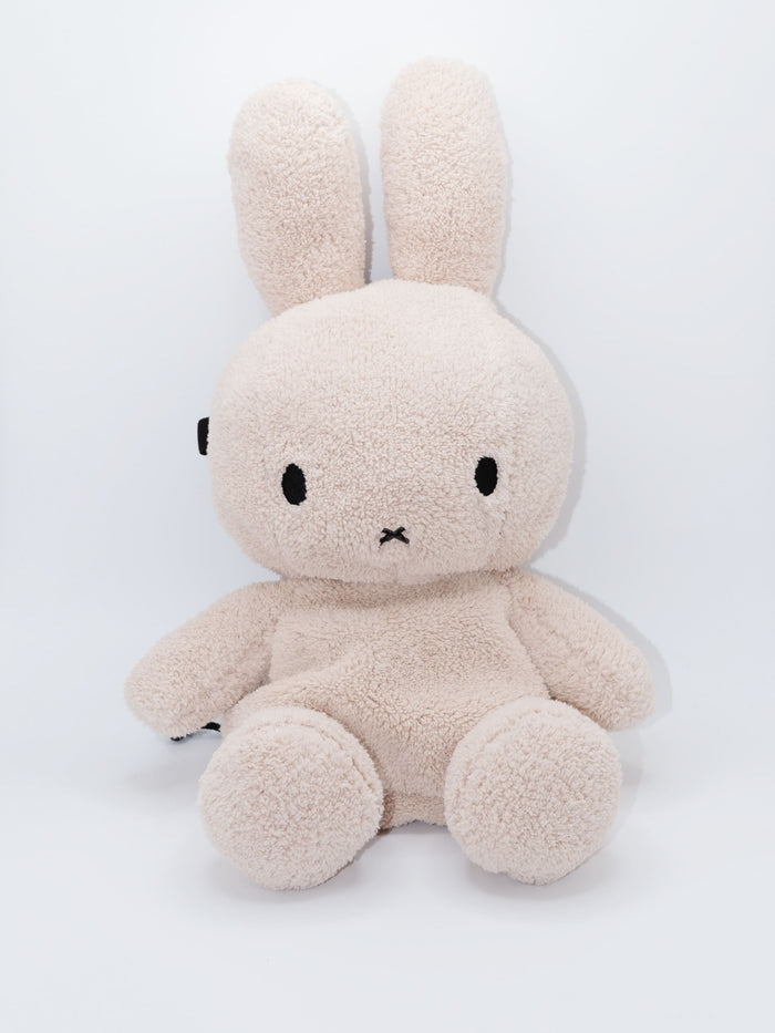 Handmade cream-colored Milk Tea Bunny plush climbing chalk bag with long floppy ears. Cute bouldering gift featuring a reinforced 12cm rim, secure drawstring, and deep black fleece lining. High-performance bouldering gear by Fatworm.