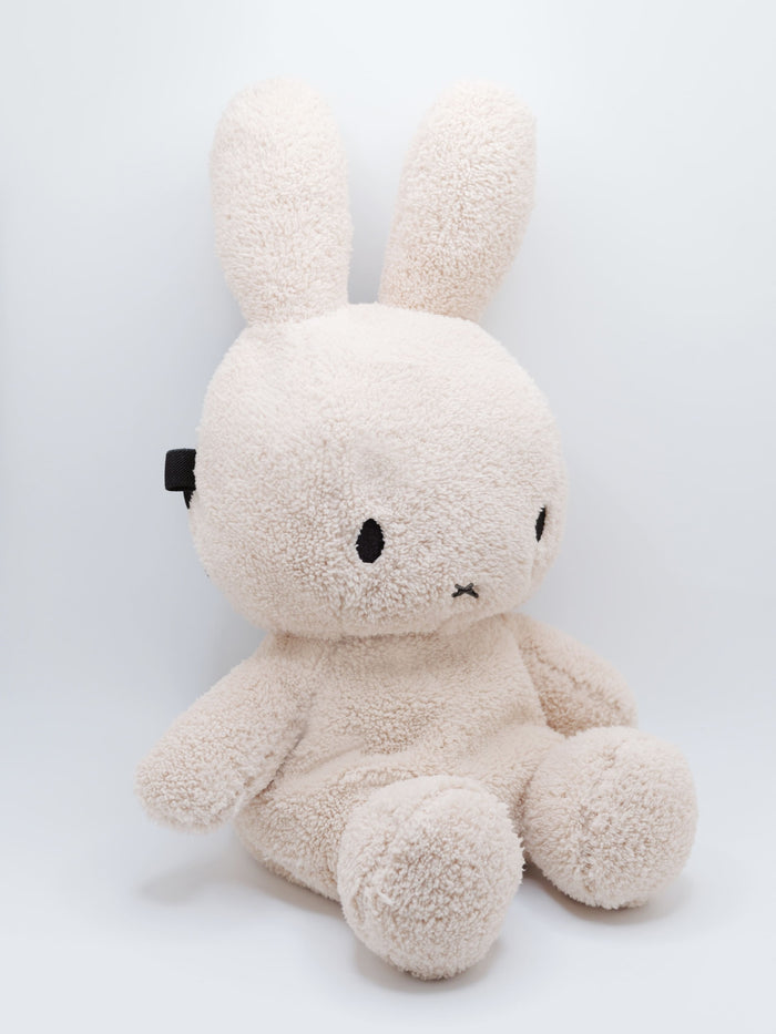 Handmade cream-colored Milk Tea Bunny plush climbing chalk bag with long floppy ears. Cute bouldering gift featuring a reinforced 12cm rim, secure drawstring, and deep black fleece lining. High-performance bouldering gear by Fatworm.