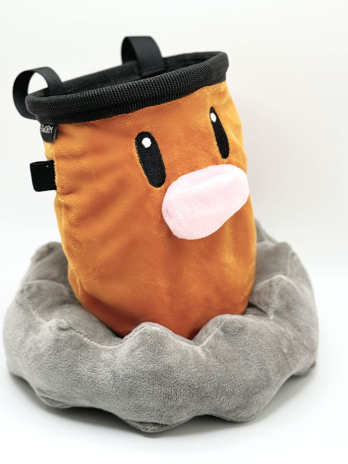 A derpy brown Diglett on a cute plush chalk bag for rock climbing. This functional salamander plush features a cheerful face and makes a hilarious climbing gift for climbers.
