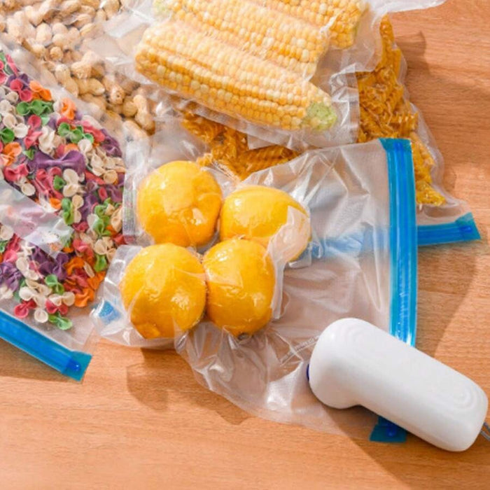 The image shows the handheld 6-in-1 vacuum device sealing zip-lock bags filled with food items like fruits, pasta, and corn, demonstrating its use for vacuum food storage and preservation.