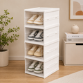 Stack of white shoe storage boxes with shoes inside, placed on a wooden floor.