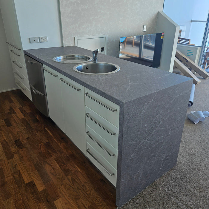 Modern kitchen island with grey countertop and stainless steel sink
