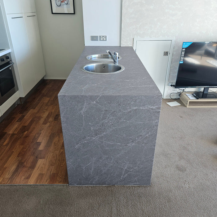 Modern kitchen with grey marble island and wooden floor.