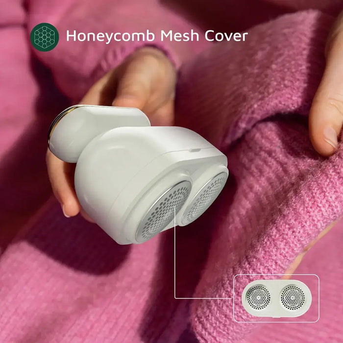 A person using the Green Lion DualPro Digital Fabric Remover on a pink sweater. The device features a honeycomb mesh cover designed to safely remove lint and fuzz without damaging the fabric. The close-up highlights its dual-head mesh design for efficient and even fabric care.