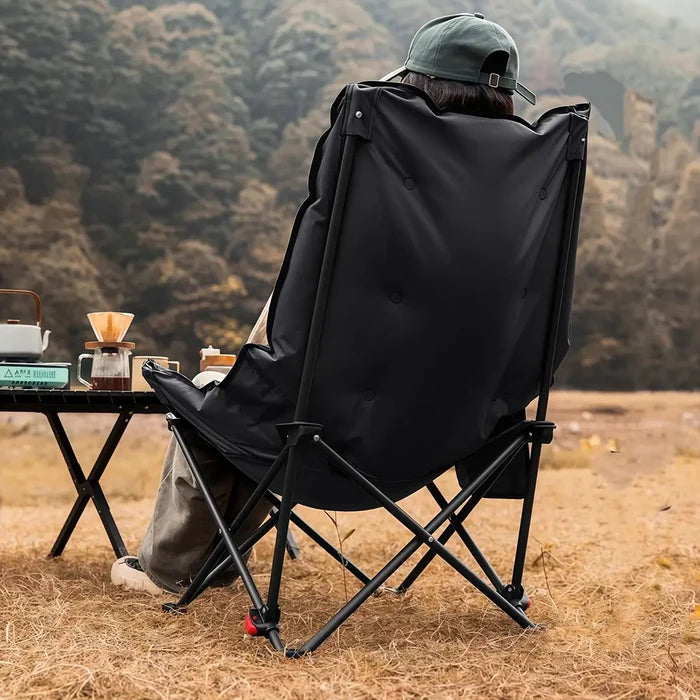 Person sitting in a black Green Lion Travix Camping Chair with a scenic background