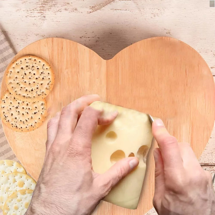 A Person is Cutting Cheese By Placing On Heart-shaped wooden cheese board.