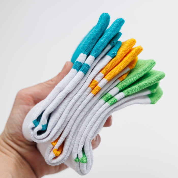 Landyn kids socks: hand holding a stack of white and colorful socks. Squid Socks, the brand seen on Shark Tank.